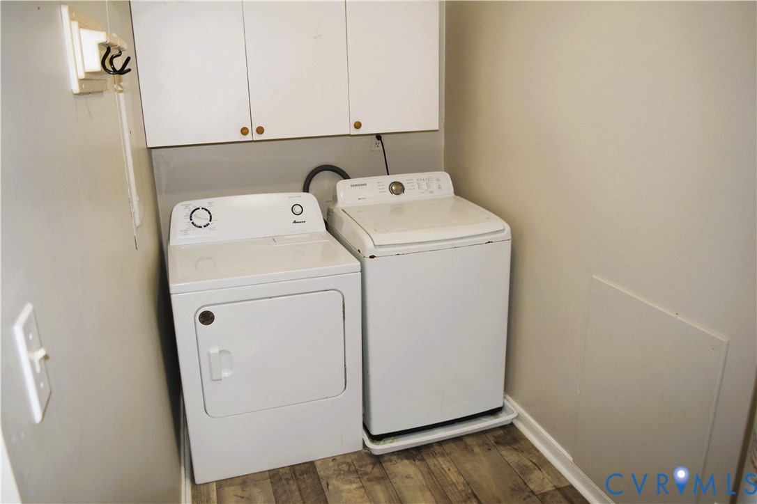 Laundry area featuring wood-finish flooring and white upper cabinetry