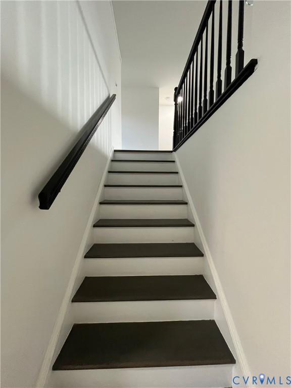 Staircase featuring dark-toned treads, crisp white risers, and a high-contrast black handrail with matching balusters