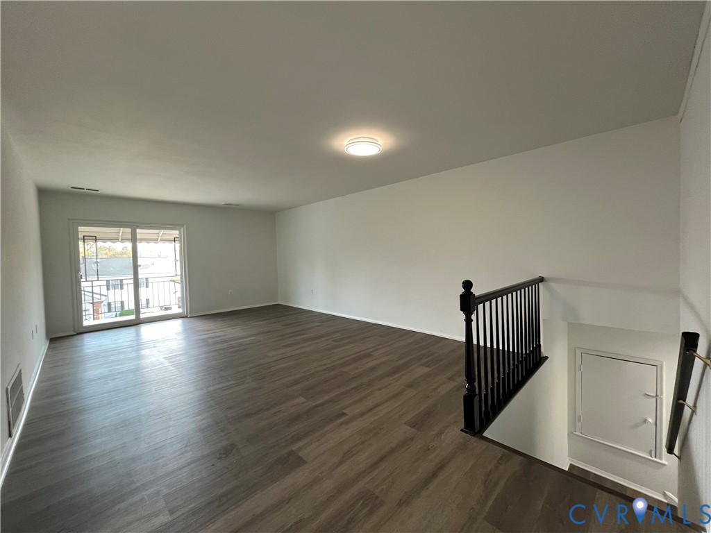 Open-concept room featuring wood-finish flooring, sliding glass door, flush-mount ceiling lighting, and a black metal spindle railing