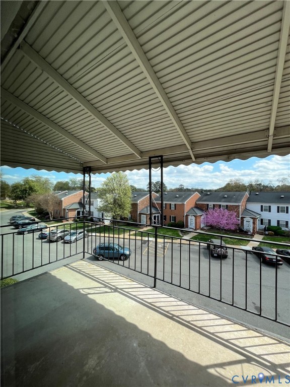 Covered balcony featuring concrete flooring and black metal railing
