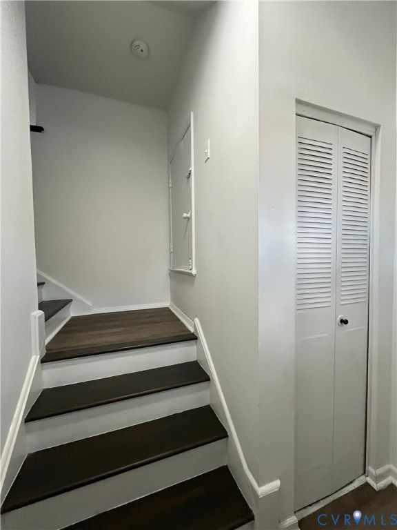 Staircase featuring wood-finish treads and white risers, accompanied by a bi-fold louvered closet door