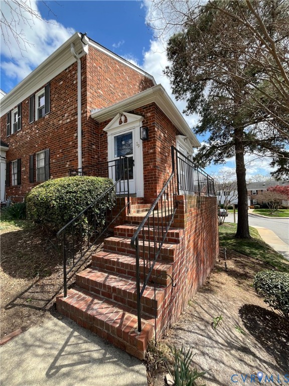 Classic brick exterior featuring a raised entry staircase, wrought iron railings, and a pedimented door surround