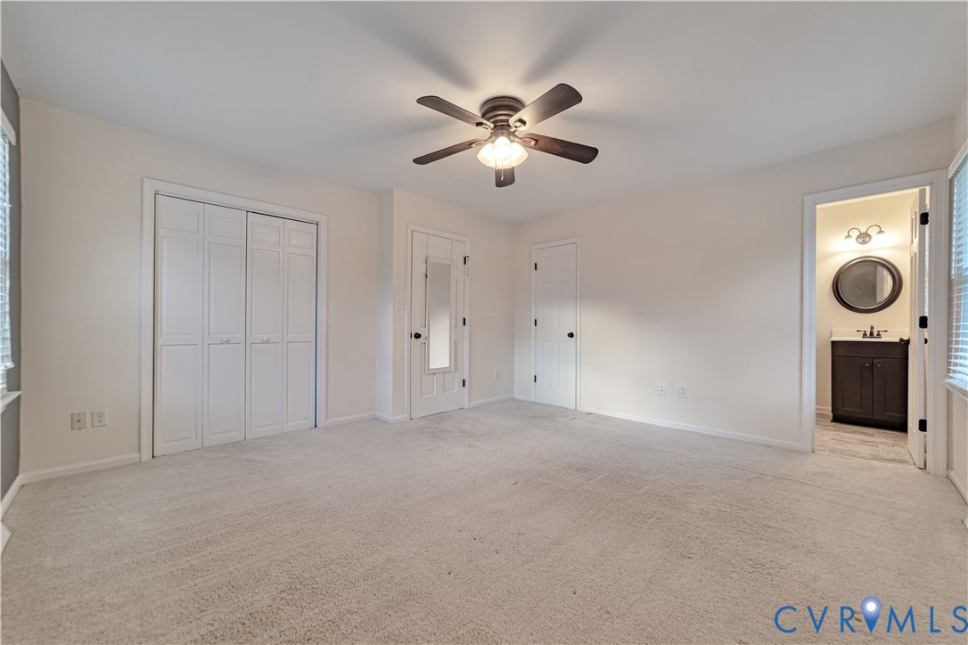 Neutral-toned wall-to-wall carpeting, central ceiling fan with integrated lighting, dual-panel closet doors, and multi-panel interior doors