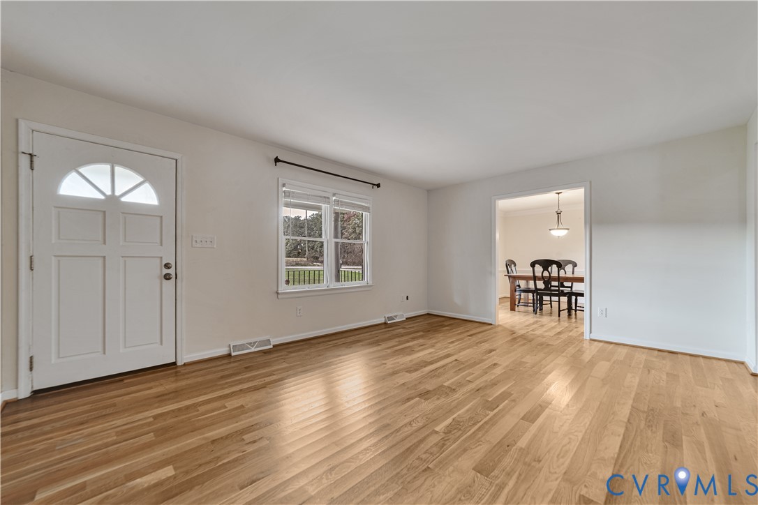 Wood-finish flooring, white paneled entry door with semi-circular window, and double-pane window with hardware Wood-finish flooring, white paneled entry door with semi-circular window, and double-pane window with hardware