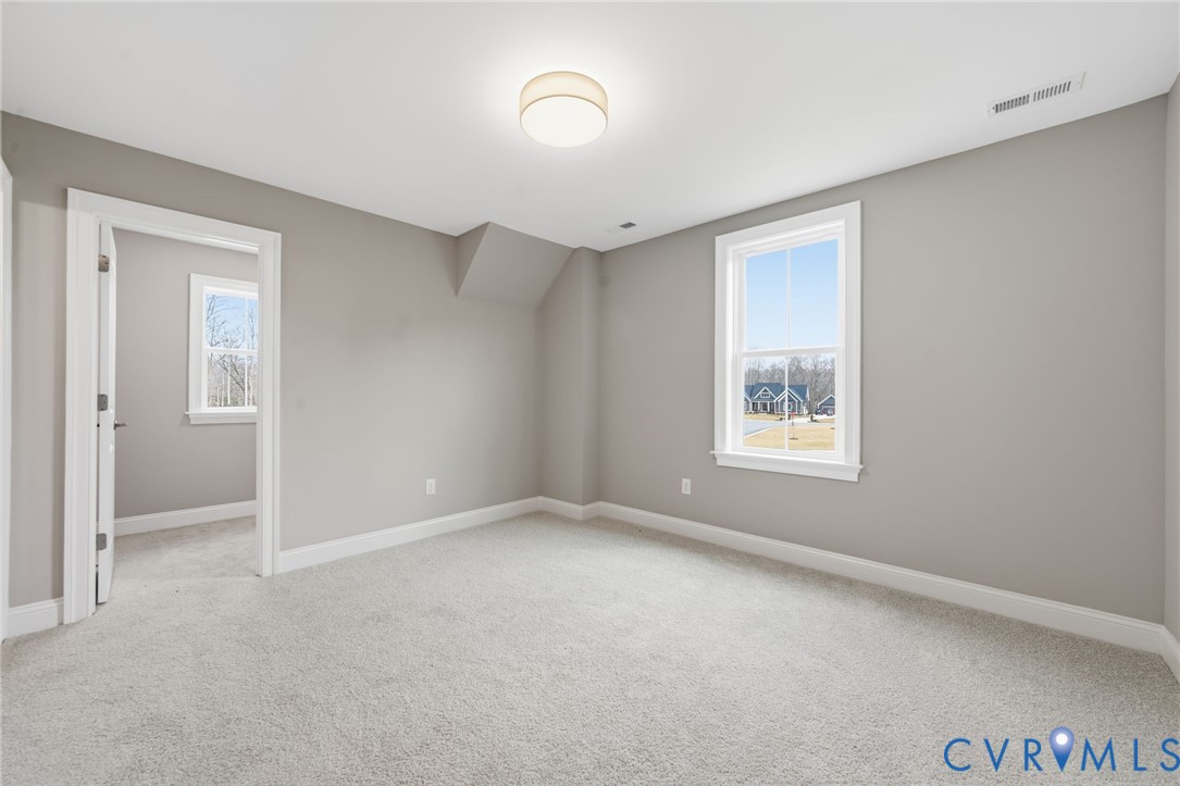 Neutral-toned interior space featuring wall-to-wall carpeting, a flush-mount drum light fixture, and multi-pane window with white trim
