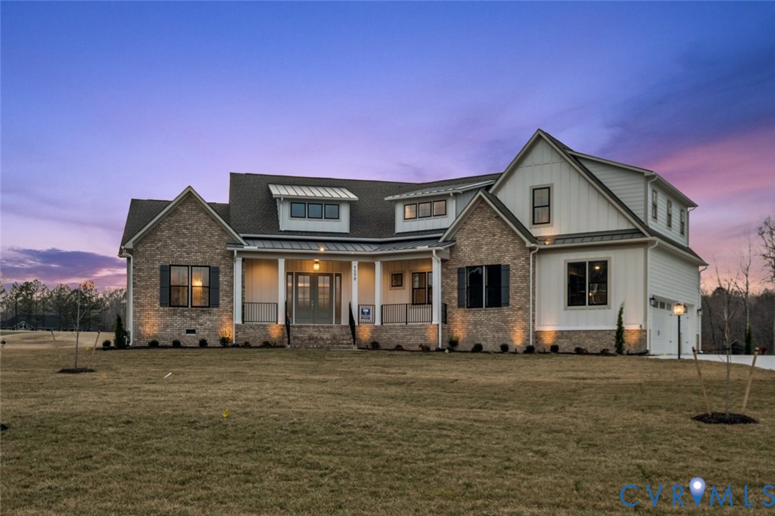 Exterior facade featuring a combination of brick and board-and-batten siding, a covered front porch with metal roofing accents, and multi-gabled rooflines