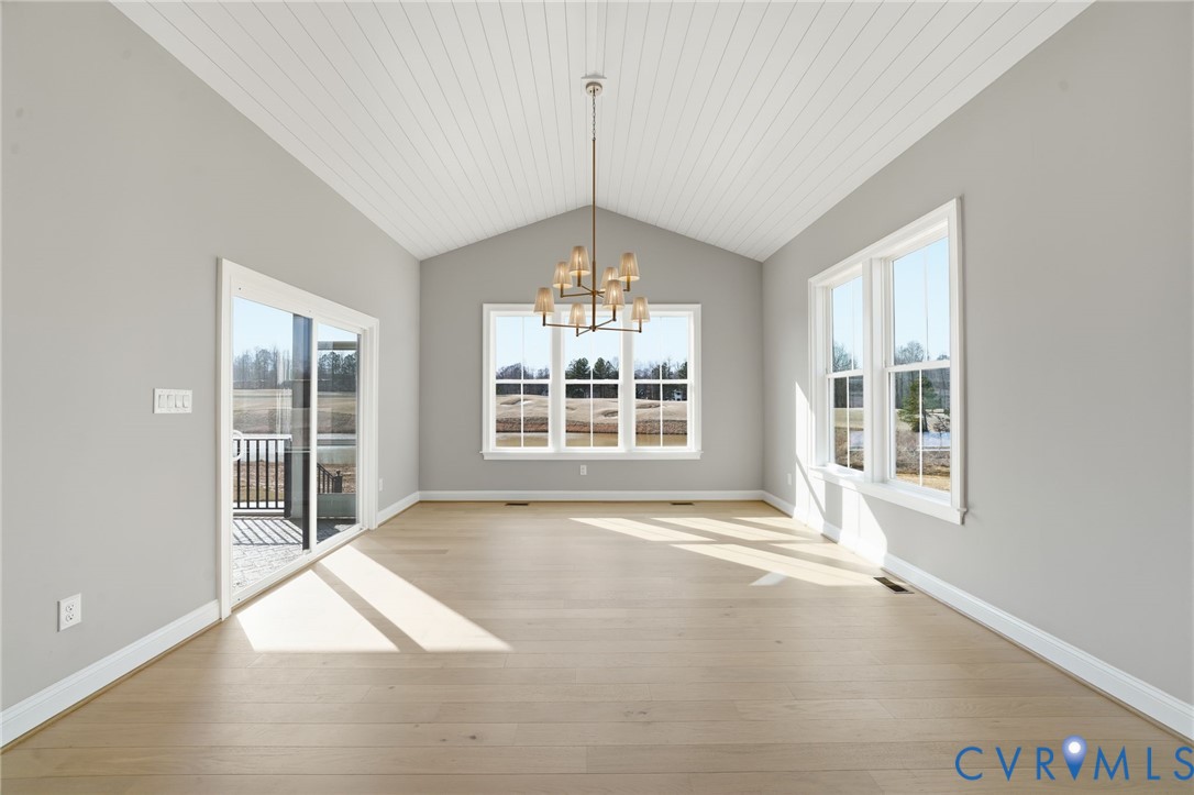 Vaulted tongue-and-groove ceiling, wood-finish flooring, multi-light chandelier, double-hung windows, and sliding glass door