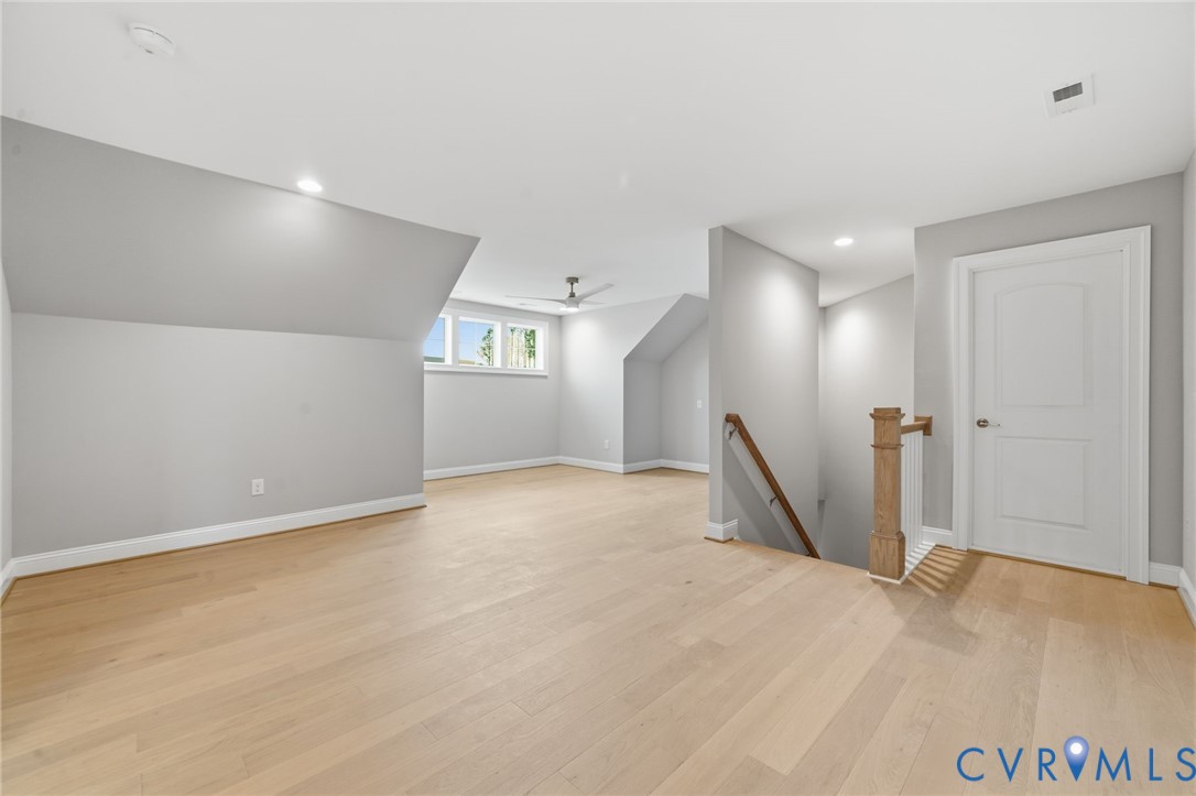 Vaulted ceilings, wood-finish flooring, recessed lighting, ceiling fan, and staircase with wooden handrail