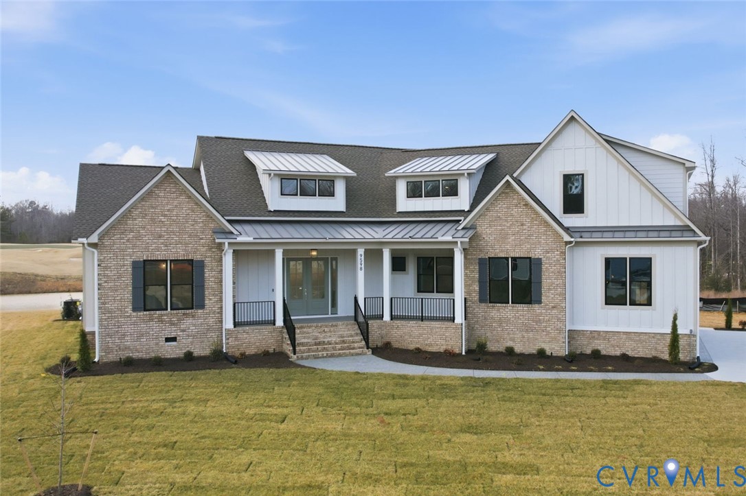 Custom-built exterior featuring a multi-material facade of brick and vertical siding, dual shed dormers, standing-seam metal roofing accents, and a covered front porch with iron railings Custom-built exterior featuring a multi-material facade of brick and vertical siding, dual shed dormers, standing-seam metal roofing accents, and a covered front porch with iron railings