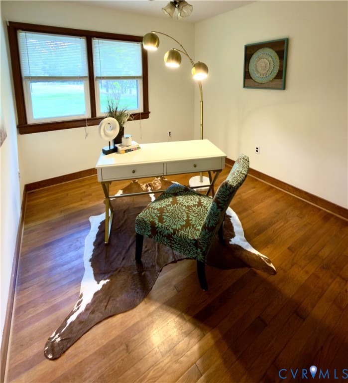 Room featuring wood-finish flooring, dark wood window trim, and a multi-light flush-mount ceiling fixture