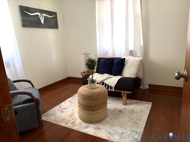 Room featuring hardwood-finish flooring, neutral wall tones, and windows framed with dual curtains