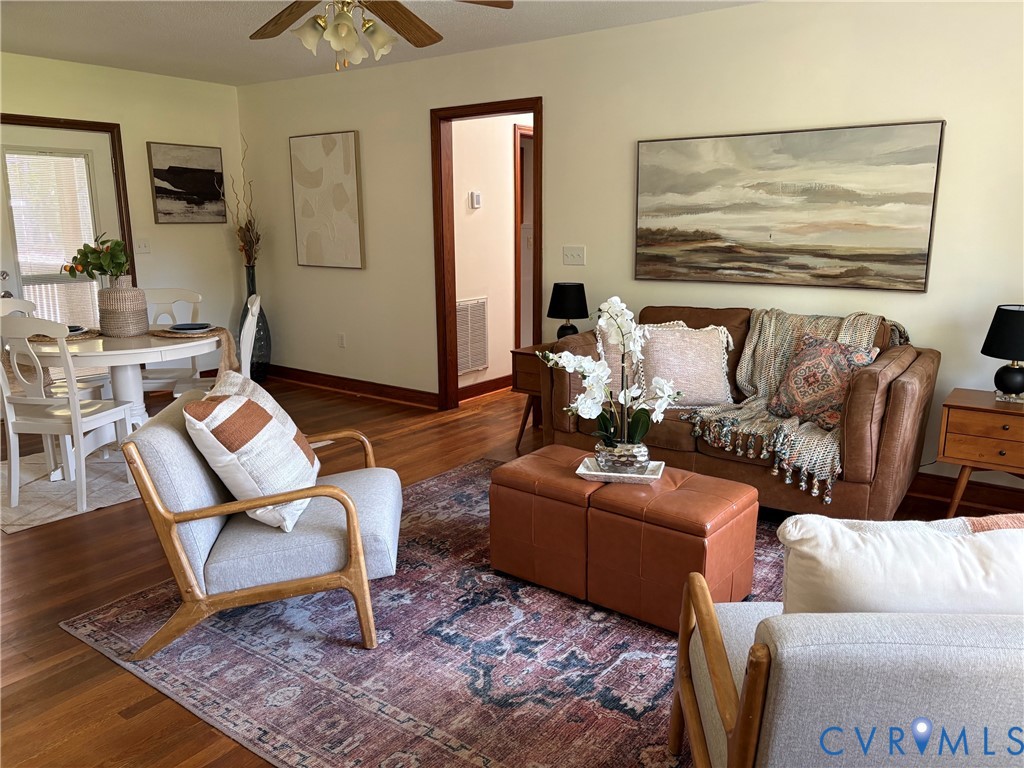 Hardwood flooring, wood-trimmed door casings, and a multi-light ceiling fan with a wooden finish