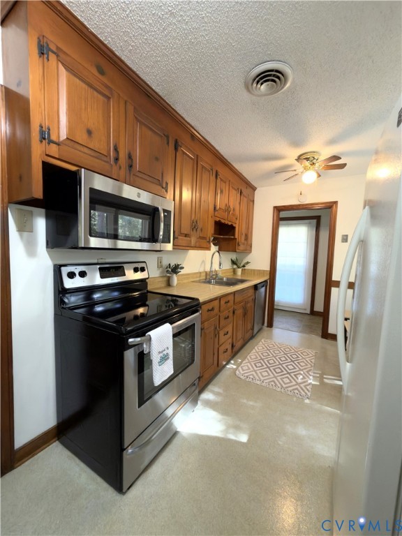Kitchen featuring custom wood cabinetry, stainless steel appliances, and integrated countertop surfaces