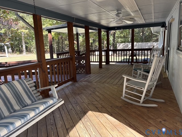 Covered wooden deck featuring a wood railing, ceiling fan, and overhead lighting