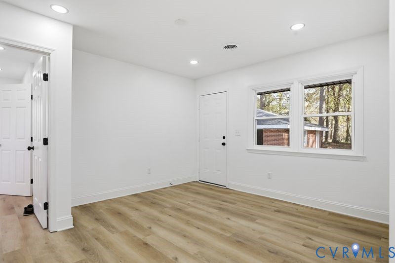Interior room featuring wood-finish flooring, recessed lighting, double-pane windows, and a solid-panel door