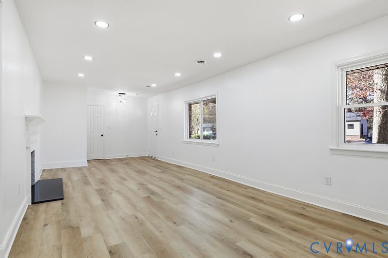 Interior space featuring wood-finish flooring, recessed lighting, double-hung windows, and a fireplace with a mantel