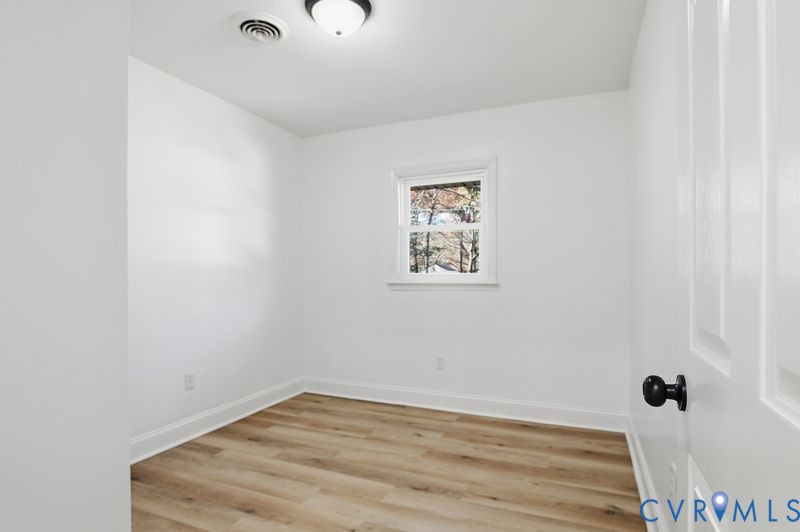 Interior space featuring wood-finish flooring, white walls, and a single-pane window