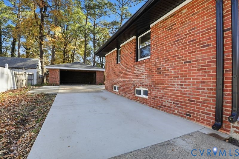 Red brick exterior featuring a concrete driveway, detached two-car garage, and dark-toned metal trim