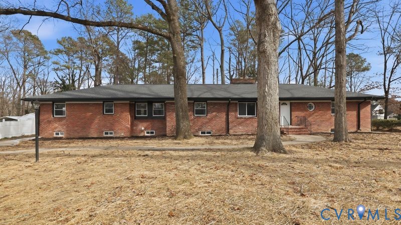 Brick exterior featuring a hip roof, chimney, circular accent window, and concrete walkway