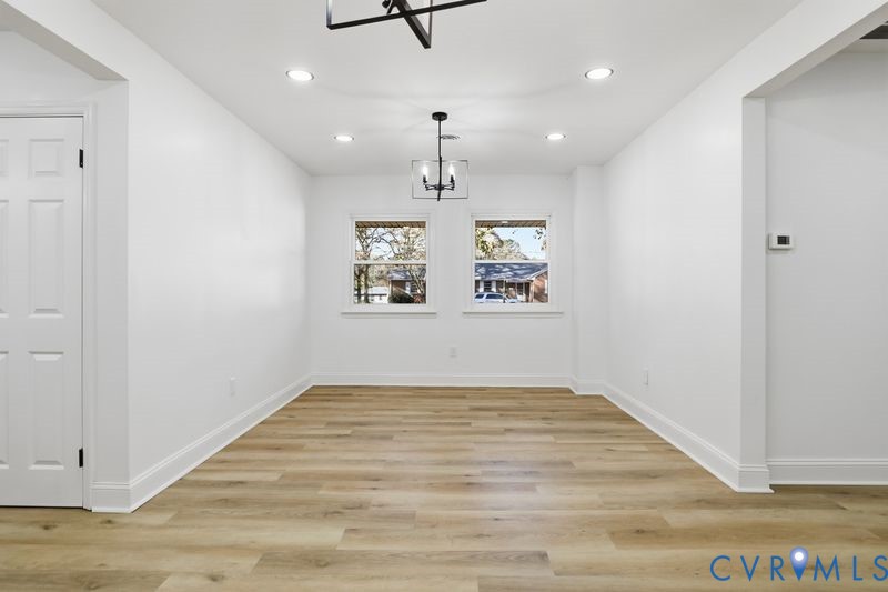 Neutral-toned wood-finish flooring, recessed lighting, and a modern tiered geometric chandelier