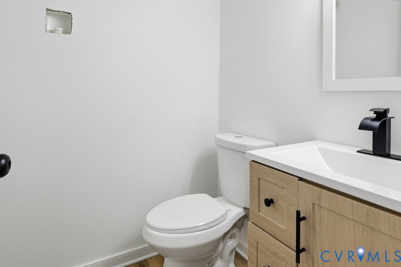 Wood-finish vanity with shaker-style cabinetry, matte black hardware, white countertop, and modern matte black faucet