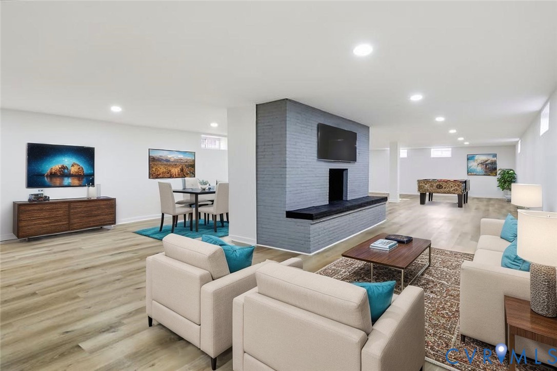 Open floor plan featuring wood-finish flooring, recessed lighting, and a central floor-to-ceiling painted brick fireplace with a built-in bench