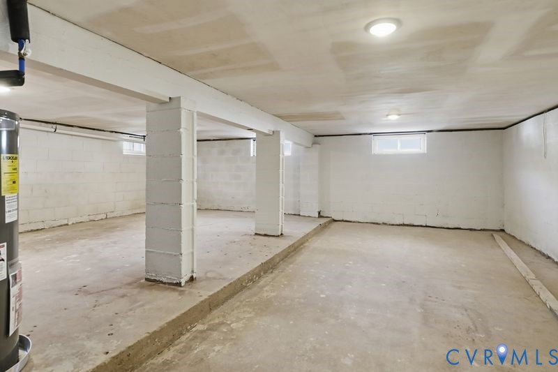 Unfinished lower level featuring painted masonry block walls, concrete flooring, structural support columns, and inset ceiling lighting