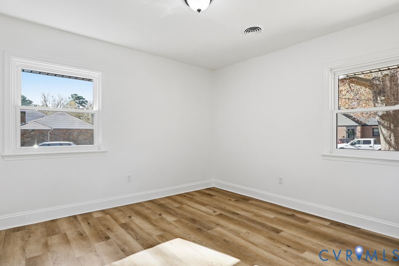 Neutral interior featuring wood-finish flooring, white walls, and dual double-hung windows