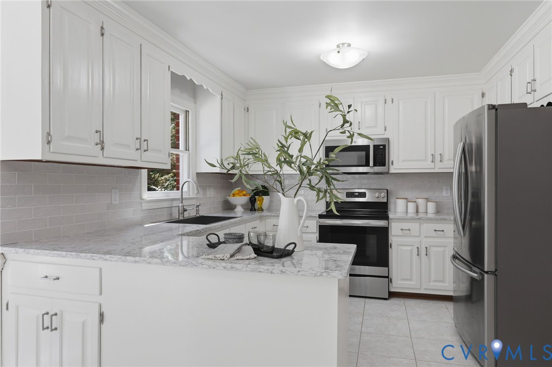 Kitchen featuring white cabinetry, stone countertops, stainless steel appliances, a tile backsplash, and ceramic tile flooring