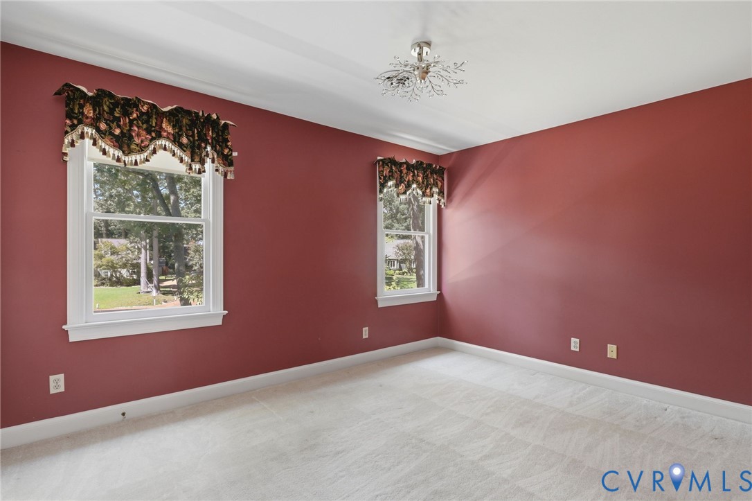 Interior space featuring neutral carpeting, double-hung windows, and a decorative multi-arm ceiling fixture