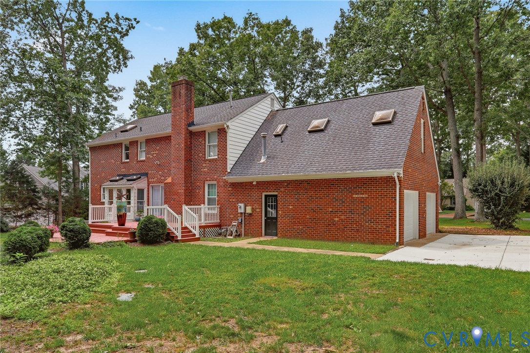 Brick exterior featuring a multi-gabled roofline, three roof-mounted skylights, a raised wooden deck with railings, and an attached two-car garage