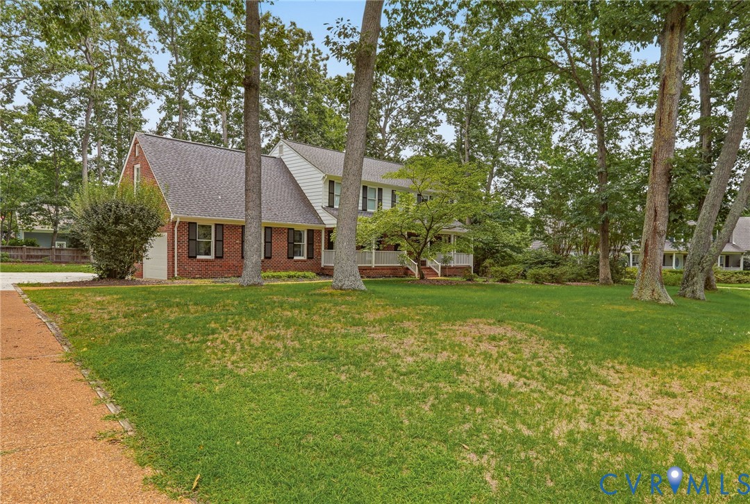 Two-story residence featuring a brick and siding exterior, front porch with white railing, and mature trees situated on a spacious lot Two-story residence featuring a brick and siding exterior, front porch with white railing, and mature trees situated on a spacious lot