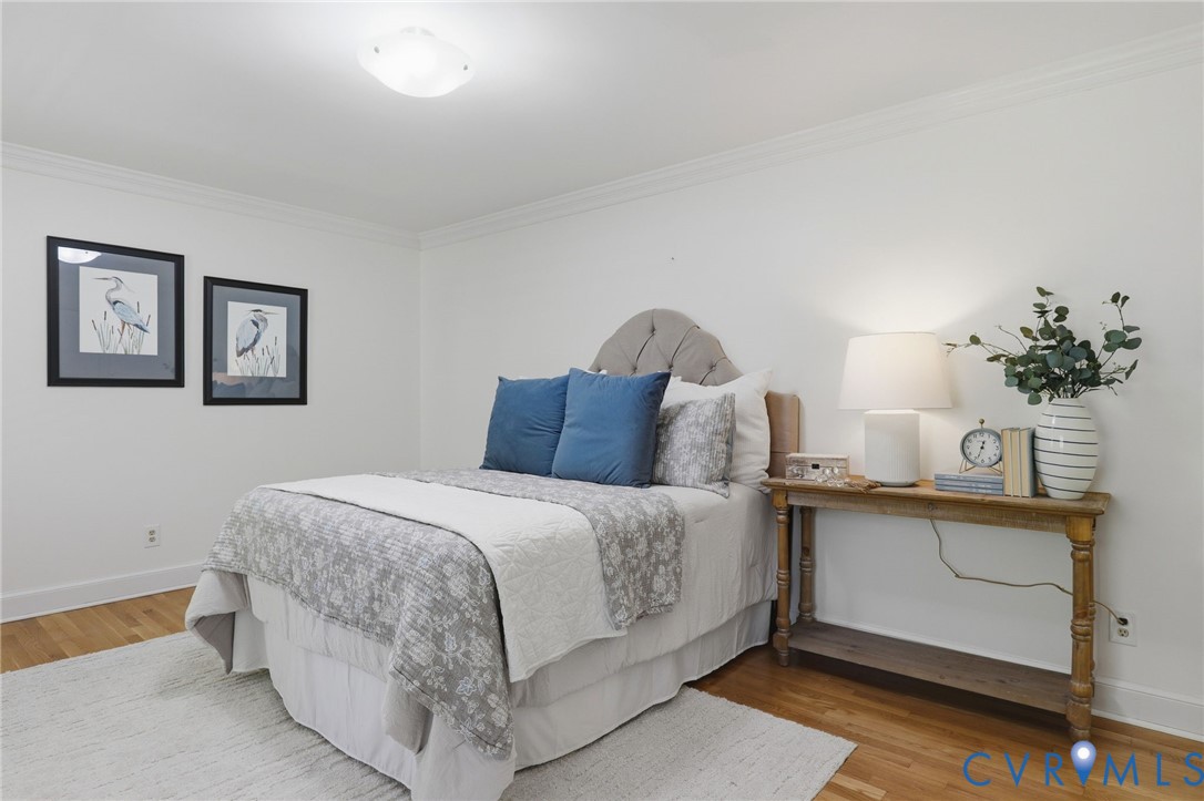 Neutral-toned walls with crown molding, wood-finish flooring, and a flush-mount ceiling light