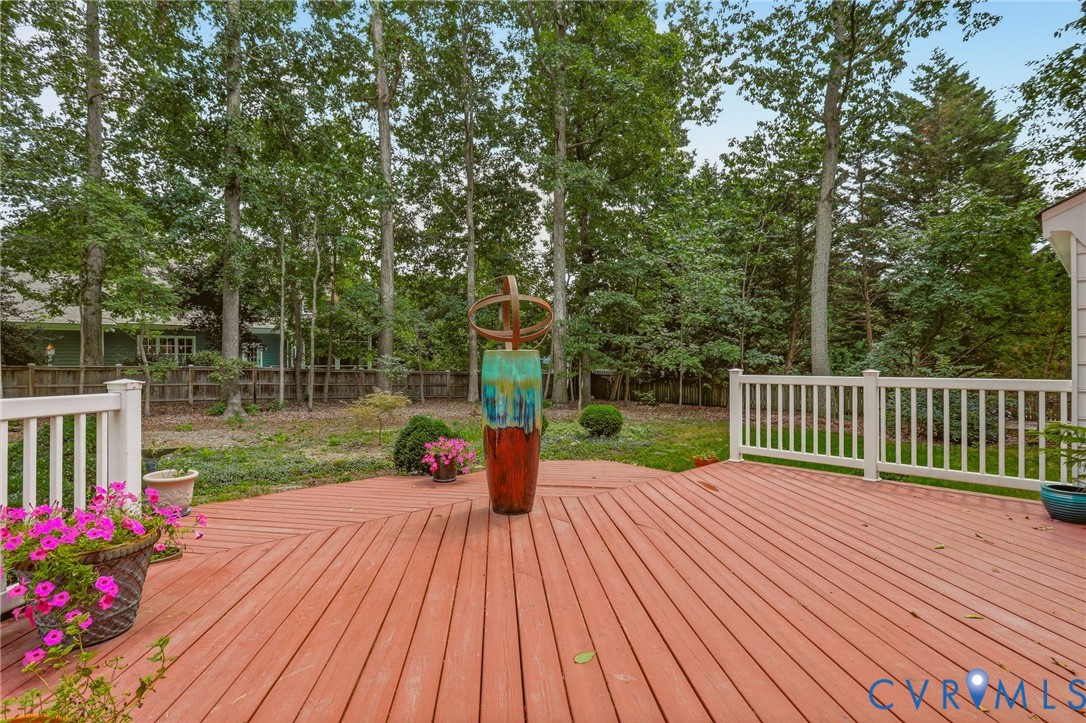 Expansive wooden deck featuring horizontal planking, white railing, and mature woodland backdrop