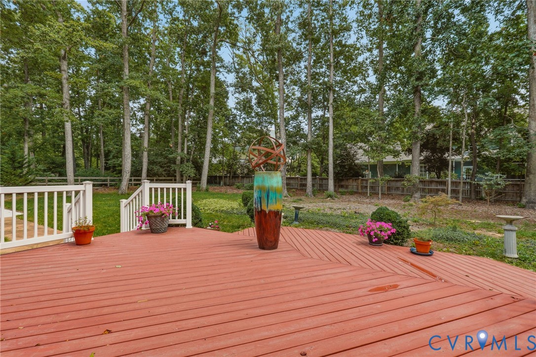 Spacious wooden deck with white railings, mature perimeter trees, and a fenced rear yard