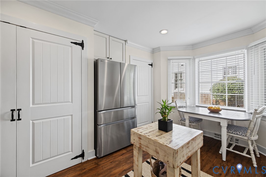 Stainless steel refrigerator, wood-finish flooring, recessed lighting, crown molding, and bay windows
