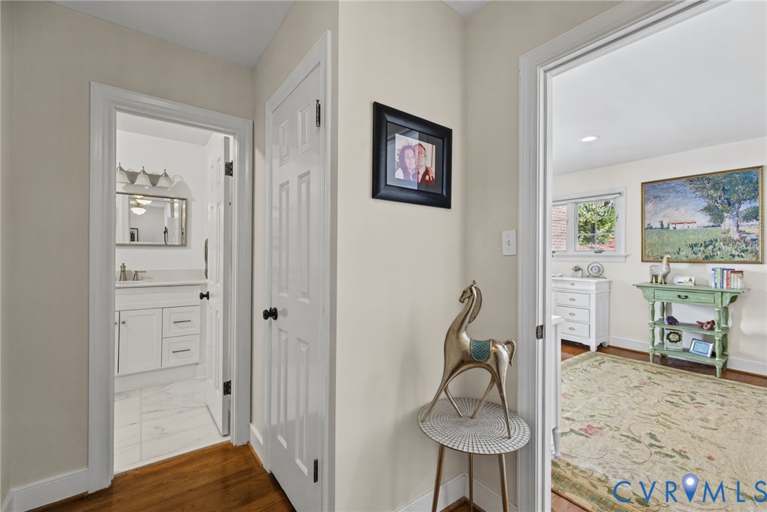 Interior hallway featuring hardwood flooring, six-panel interior doors with matte black hardware, and crisp neutral wall paint