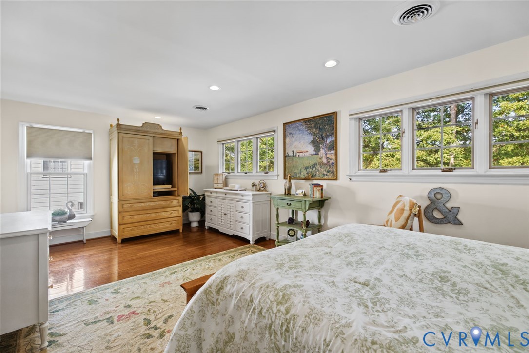 Spacious room featuring wood-finish flooring, multi-pane windows, and recessed lighting