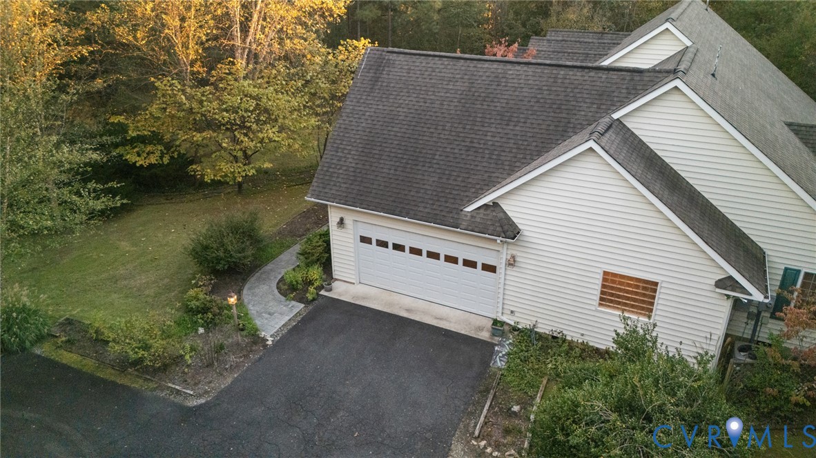 Exterior featuring light-colored horizontal siding, asphalt shingle roof, two-car garage with transom windows, paved driveway, and stone-paver walkway