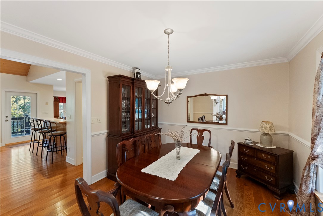Dining room featuring crown molding, chair rail trim, and hardwood flooring
