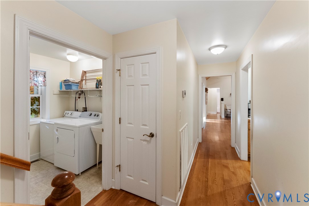 Hallway featuring wood-finish flooring and multiple paneled interior doors, with a dedicated utility room containing wire shelving and a basin sink