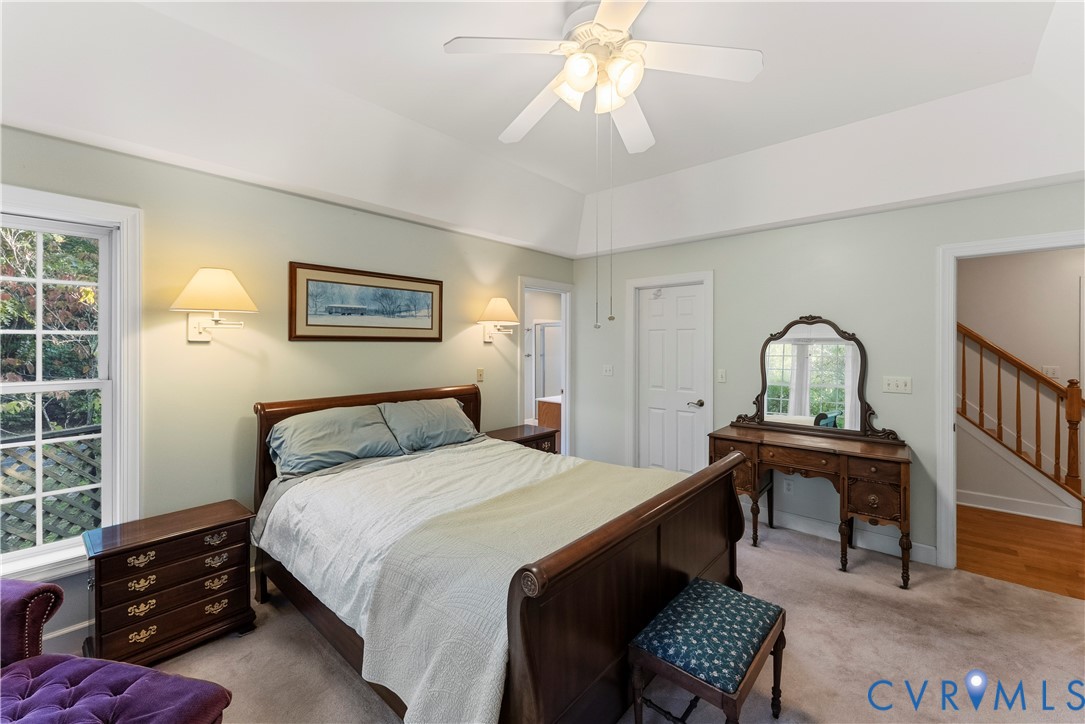 Tray ceiling, neutral wall tones, multi-pane window, wall-mounted sconce lighting, and a ceiling fan with integrated light fixture