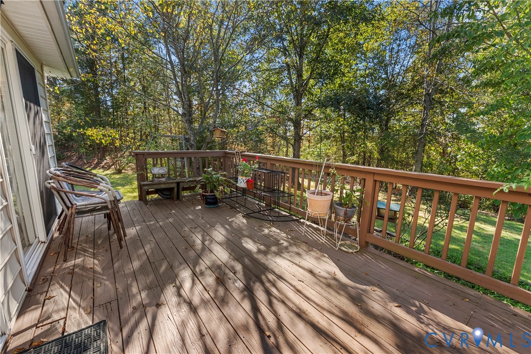 Elevated wood deck featuring vertical wood balusters and a sloped rear yard with mature trees