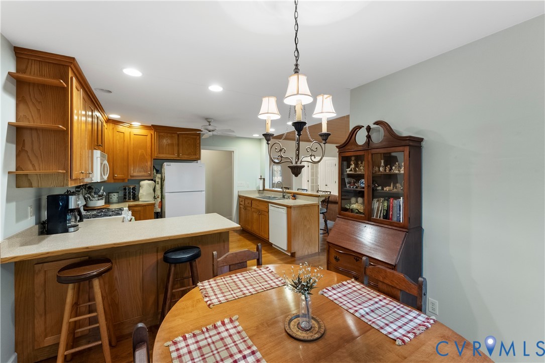 Kitchen featuring wood cabinetry, solid-surface countertops, a peninsula with bar seating, and a decorative multi-arm chandelier