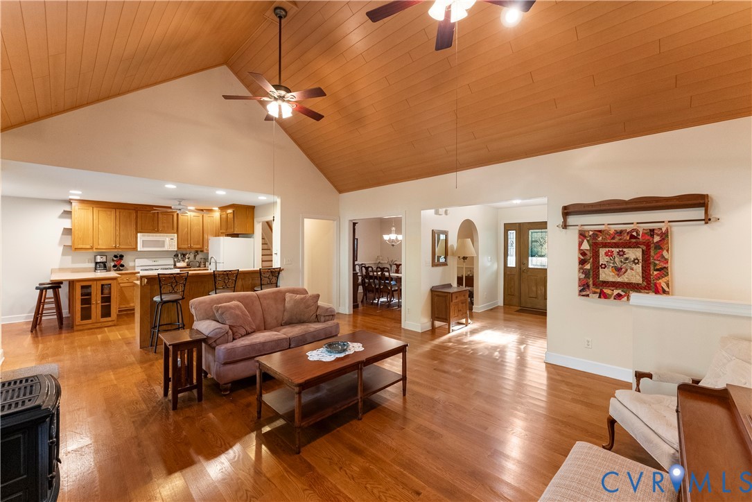 Vaulted ceiling with wood-finish paneling, hardwood flooring, recessed lighting, and kitchen with wood cabinetry