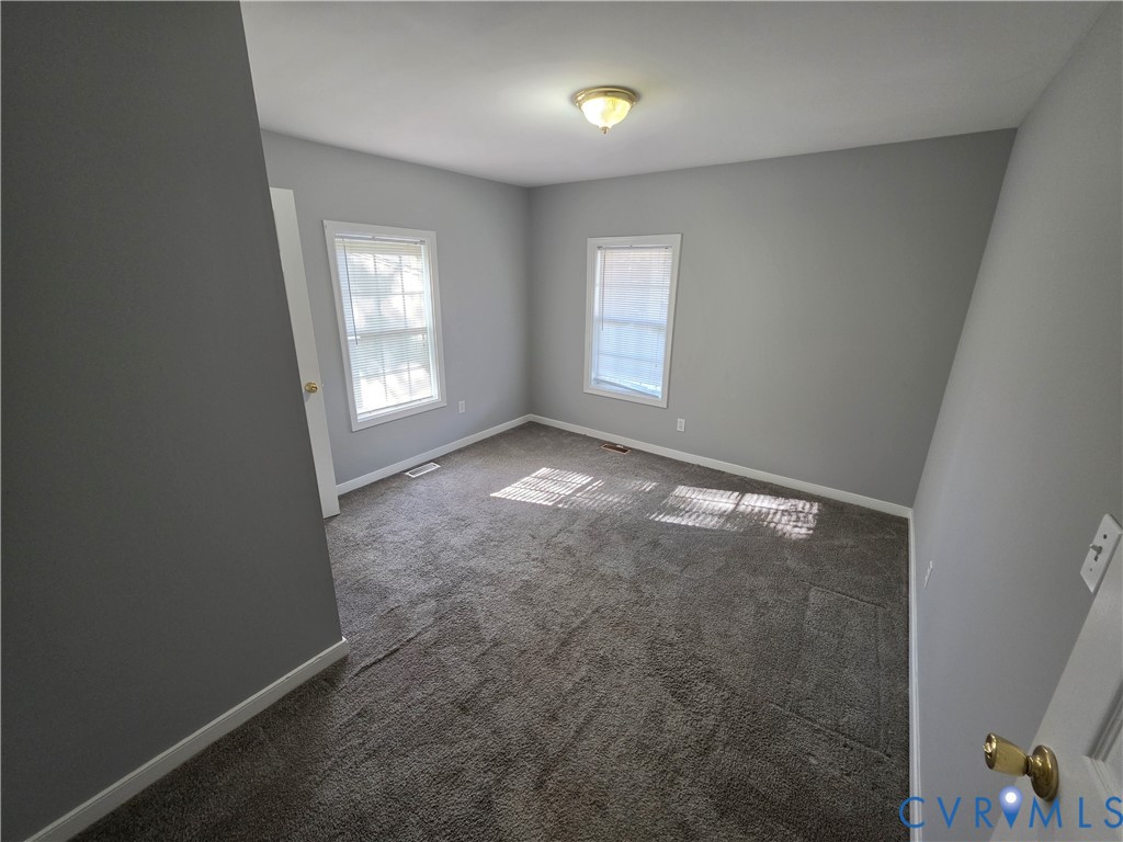 Neutral wall tones, wall-to-wall carpeting, two multi-pane windows, and a flush-mount ceiling fixture