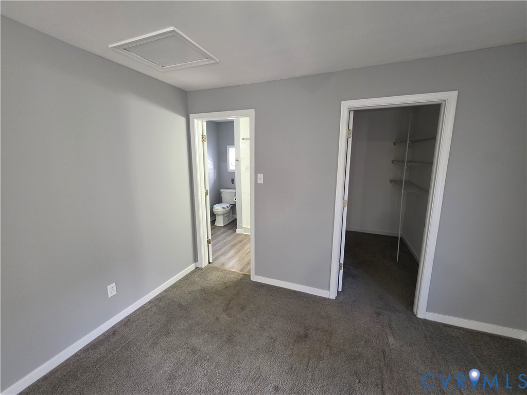 Neutral-toned interior featuring wall-to-wall carpeting, wood-finish flooring in the secondary space, and a walk-in closet with built-in shelving