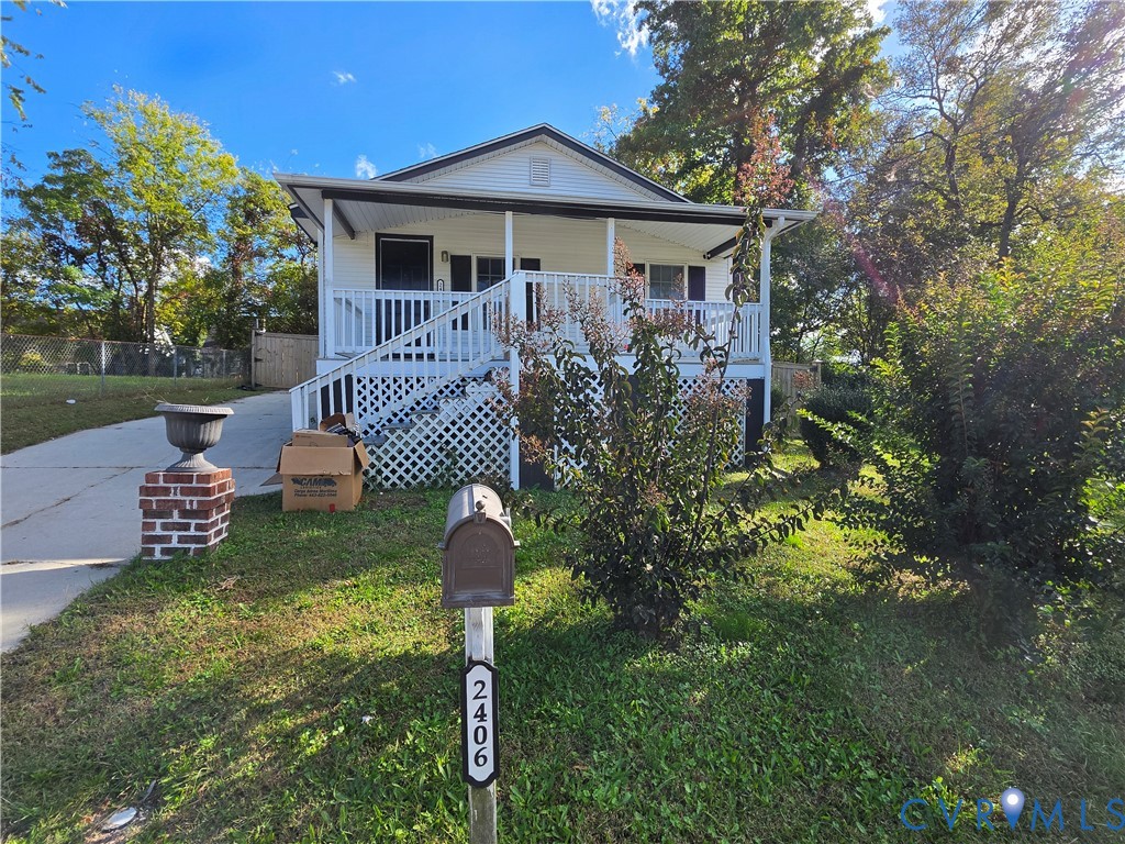 Exterior facade featuring a covered front porch, white lattice skirting, concrete driveway, and brick-column mailbox mount