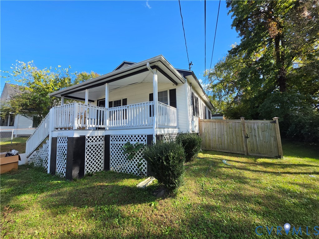 Exterior featuring light-colored horizontal siding, a raised deck with white railing, decorative lattice skirting, and a wood privacy fence