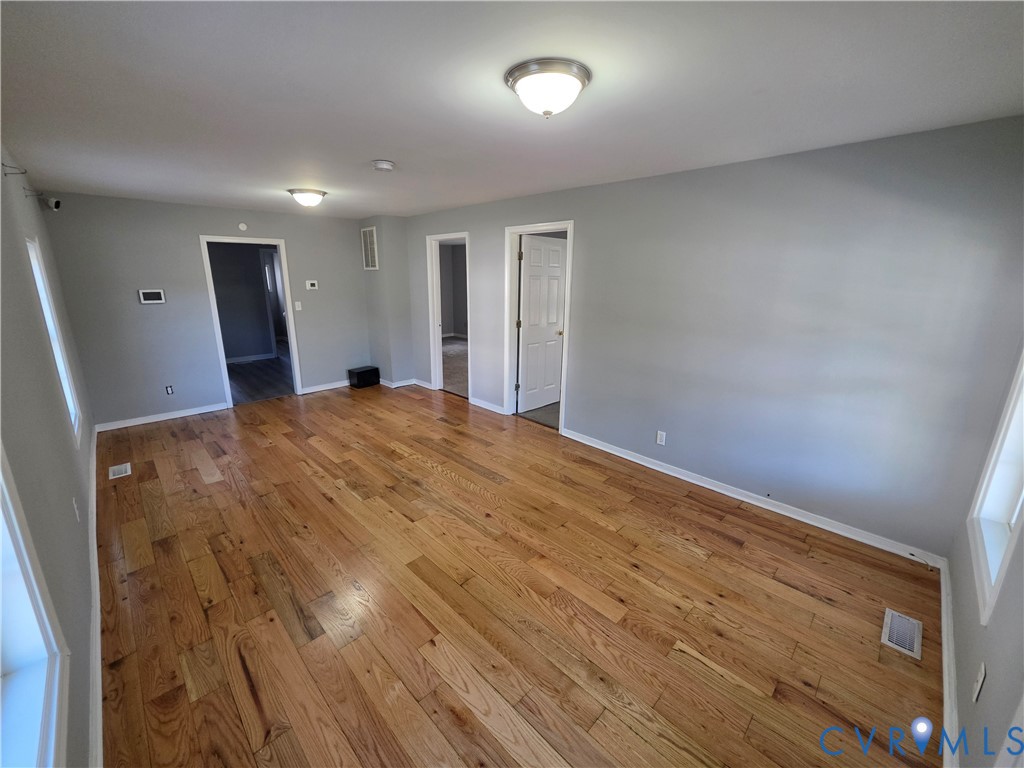 Interior room featuring wood-finish flooring, neutral wall paint, and two flush-mount ceiling light fixtures